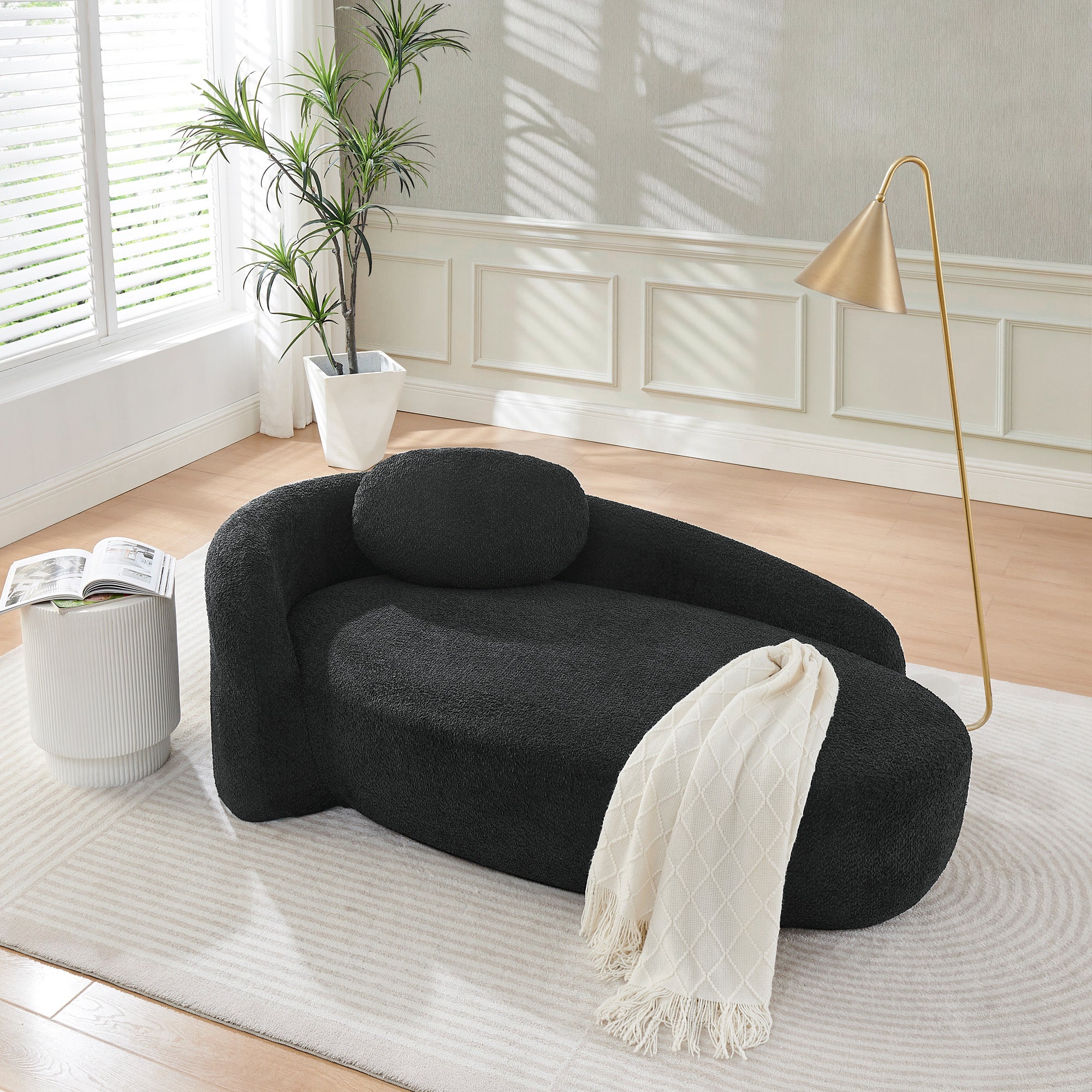 Black bouclé lounge chair beside bed in bedroom