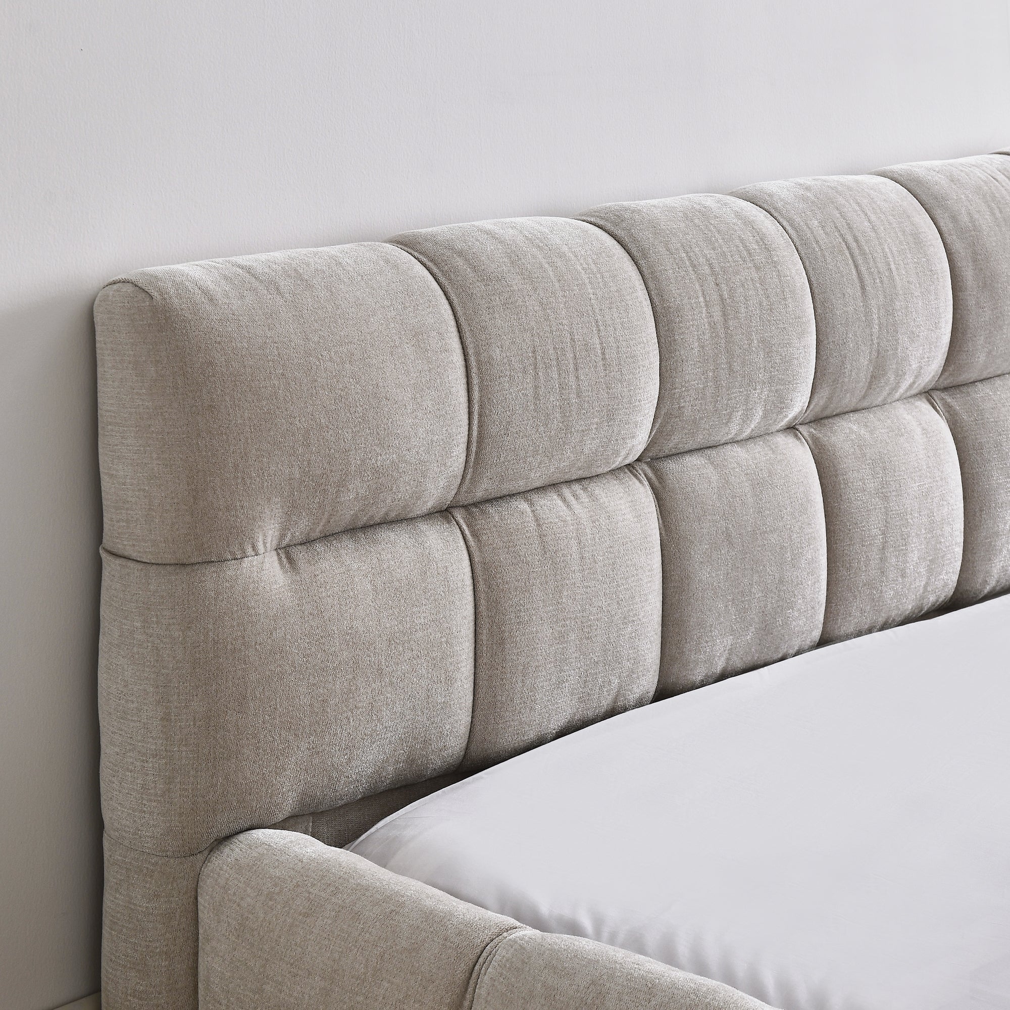 Beige upholstered bed footboard detail