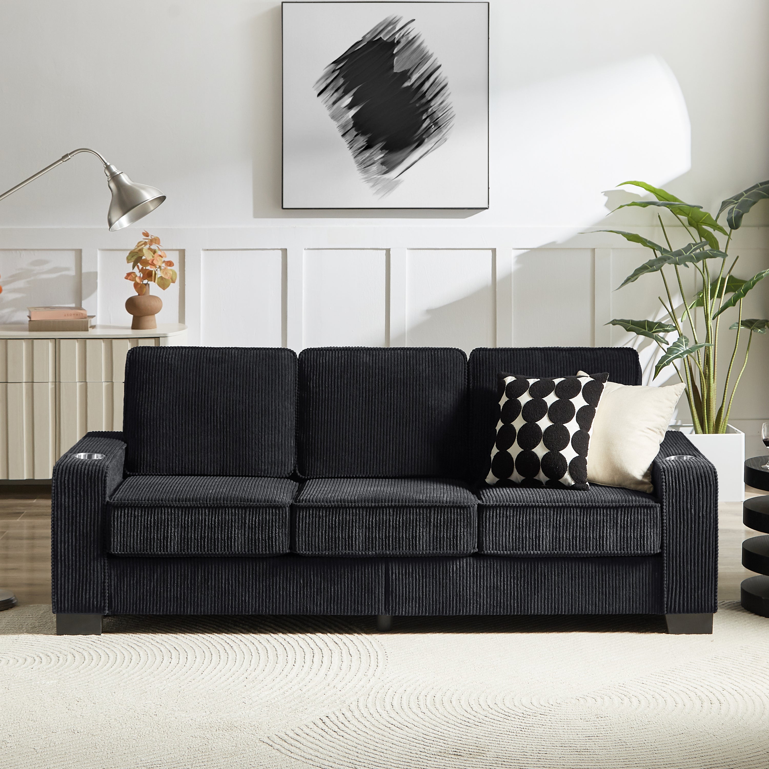 Black corduroy sofa with dual armrest cup holders side profile