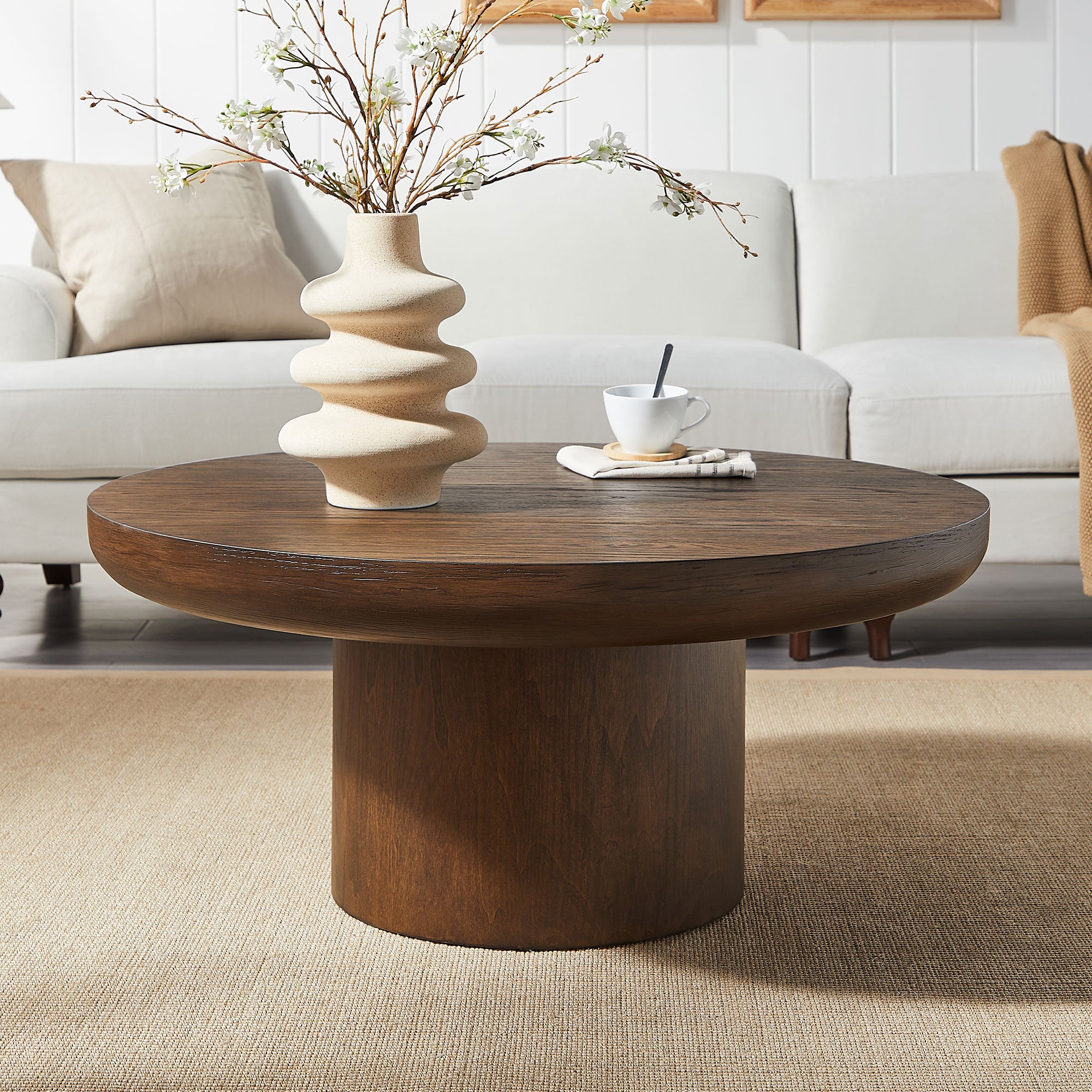 Dark brown round coffee table with cylindrical oak legs — front view
