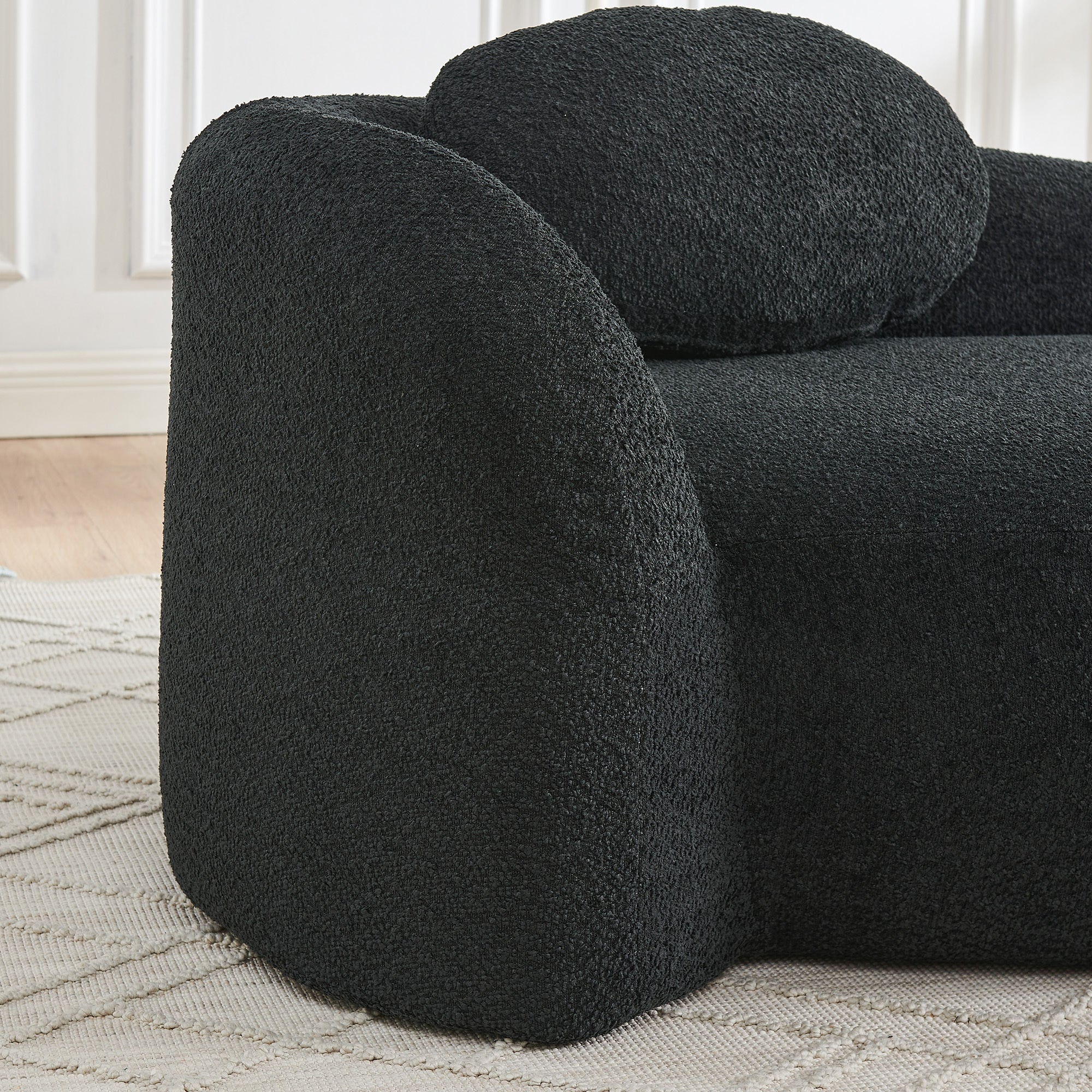 Matching pillow on black bouclé lazy lounge chair backrest